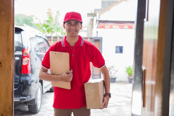 Hombre en uniforme rojo entrega caja de paquete — Foto de Stock