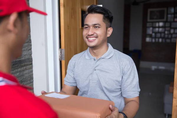 Man in red uniform delivering parcel — Stock Photo, Image