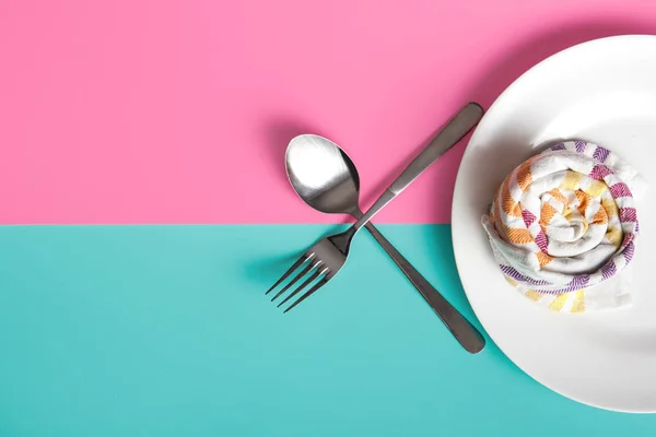Piatto bianco con tovagliolo, forchetta e cucchiaio su sfondo pastello — Foto Stock