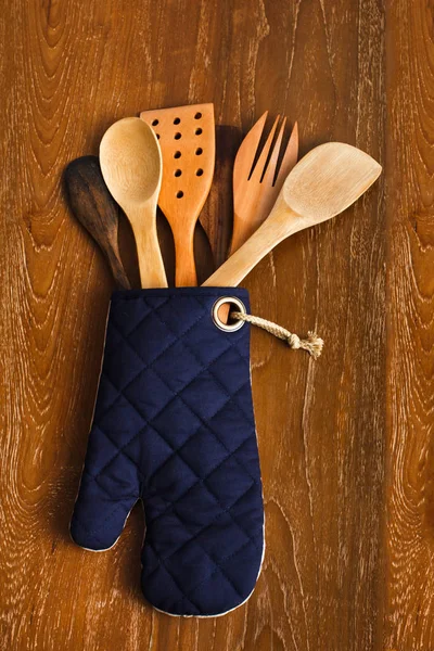 Different wooden kitchen tools  in oven gloves — Stock Photo, Image