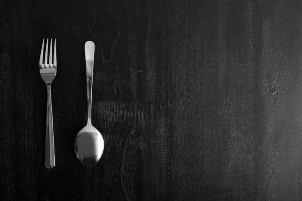 Tenedor de metal y cuchara sobre fondo negro de madera — Foto de Stock