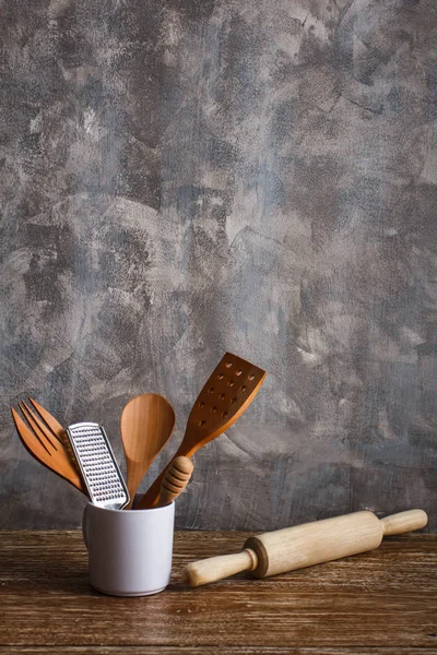 Verschiedene Küchenutensilien in weißem Becher und Nudelholz — Stockfoto