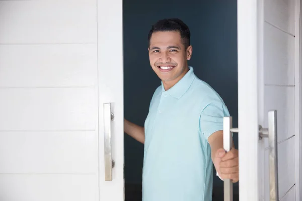 Man öppna hans främre hus dörr och leende — Stockfoto