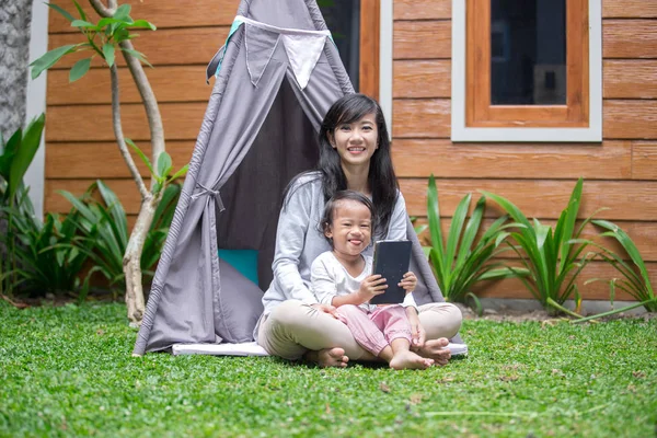 Usando la tableta mientras juegas en el patio trasero de casa — Foto de Stock