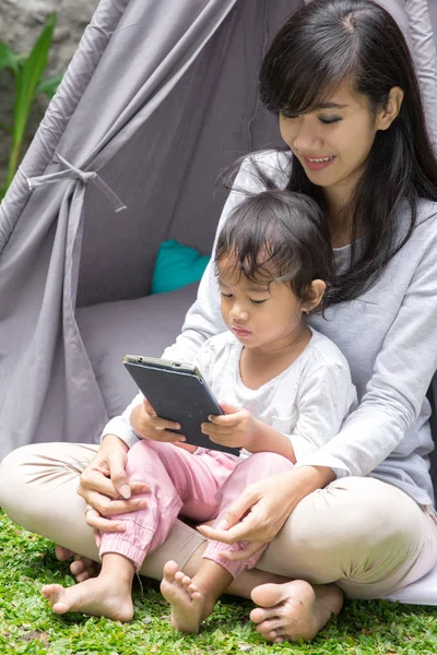 Usando tablet enquanto joga em casa quintal — Fotografia de Stock