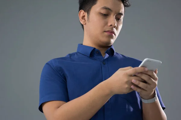 Asiático joven hombre en casual usando el teléfono móvil —  Fotos de Stock
