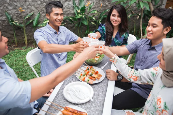 Venner som nyter mat i hagen og jubel – stockfoto