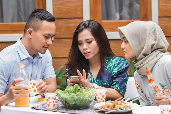 Mujer mostrando su teléfono móvil con amigos — Foto de Stock