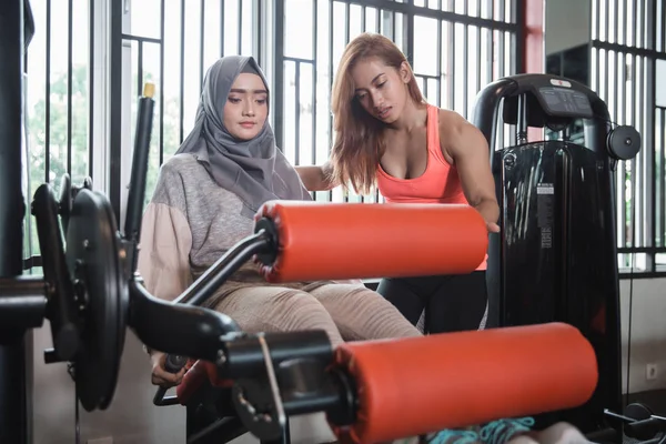 체육관에 앉아 다리 꼬고 기계 운동 무슬림 여성 hijab — 스톡 사진