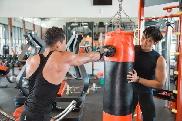 Boxer doen opleiding op een bokszak met trainer — Stockfoto