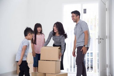 parent and kids with cardboard box. moving to new house clipart