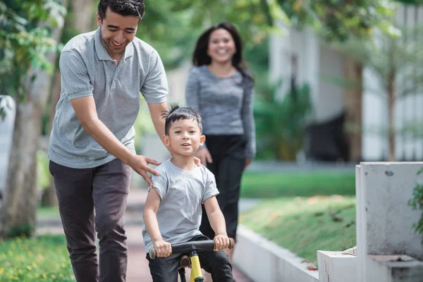 Bambini andare in bicicletta spinta da suo padre — Foto Stock