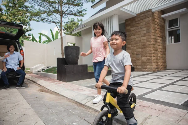 Kinder fahren Fahrrad und Schwester läuft hinter ihm her — Stockfoto