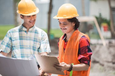 Şantiye önünde duran iki inşaat işçisi