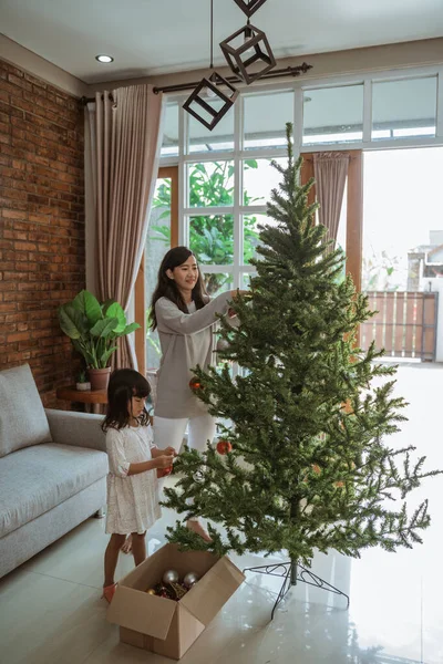 Ibu dan anak menggantung beberapa aksesoris pada pohon Natal — Stok Foto