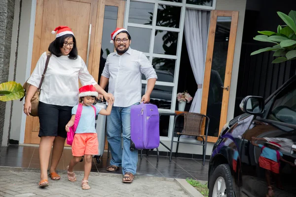 Familie met koffer die voor hun huis loopt — Stockfoto