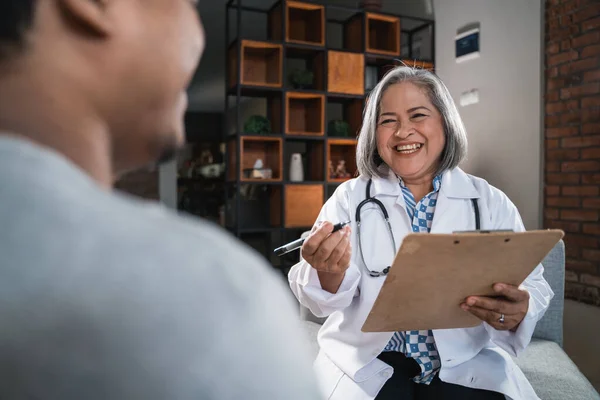 The female doctor makes notes with the clipboard when asking her patients — Stock Photo, Image