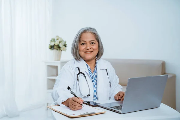 Vrouwelijke arts met een laptop op tafel — Stockfoto