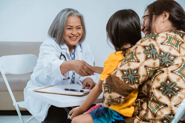 Arzt schüttelt einem Kind und seiner Mutter die Hand — Stockfoto