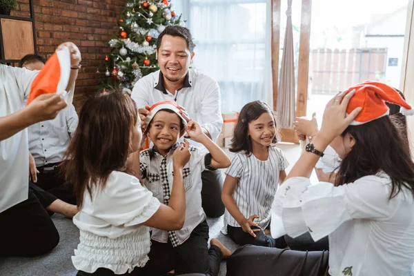 Keluarga meletakkan topi santa selama perayaan Natal — Stok Foto