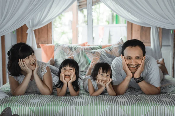 Pai, mãe e filhas relaxando juntos na cama — Fotografia de Stock