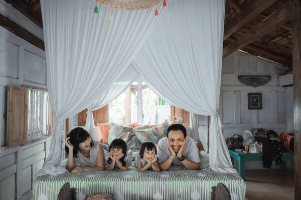 Ojciec, matka i córki relaksują się razem w łóżku — Zdjęcie stockowe