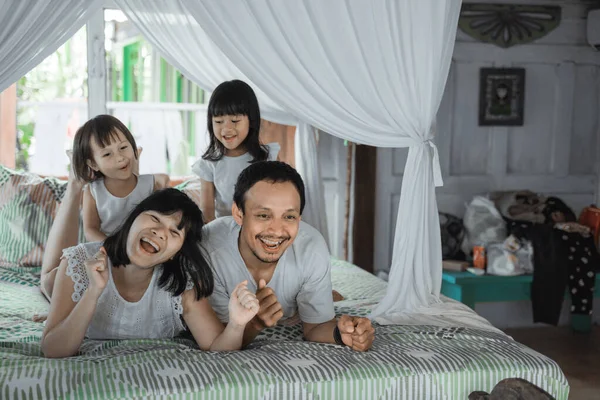Азиатская счастливая семья и дочь, отдыхающая на кровати — стоковое фото