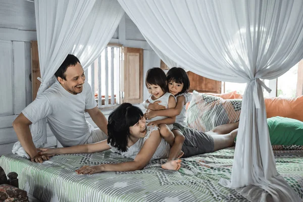 Father, mother and daughters relaxing together on bed — 图库照片