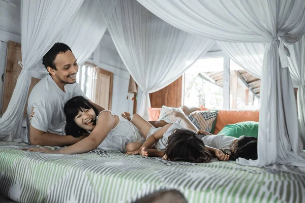 Far, mor och döttrar kopplar av tillsammans i sängen — Stockfoto