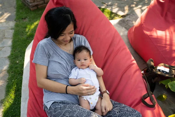 Asiatische Mutter hält Baby auf faulem Sack — Stockfoto