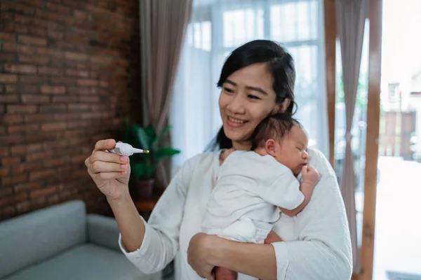 Mère avec bébé nouveau-né et thermomètre — Photo