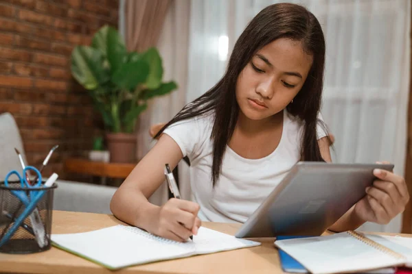 アジアのティーンエイジャーはタブレットを使って家で宿題をしています — ストック写真