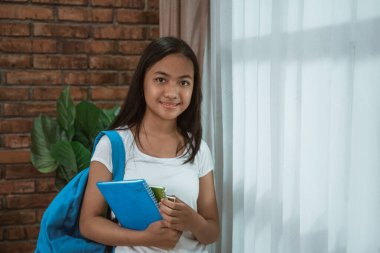 Genç Asyalı öğrenci elinde kitap tutuyor.