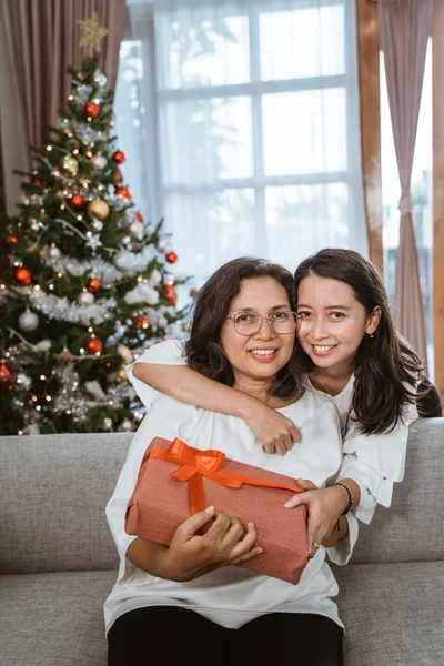Anak perempuan memberikan hadiah kejutan kepada ibu selama hari Natal — Stok Foto