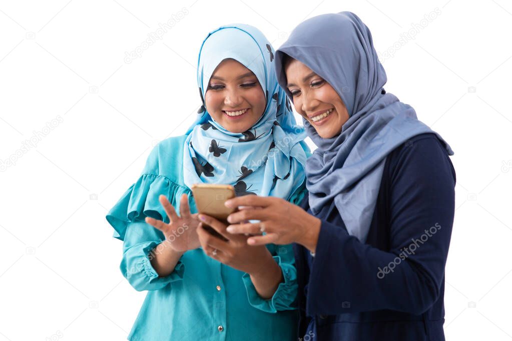 Portrait of veiled young woman showing a smartphone to her mother and together seeing it