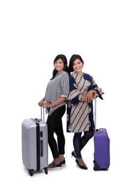 Genç kadın ve annesi ayakta ve bavullarını tutuyorlar.