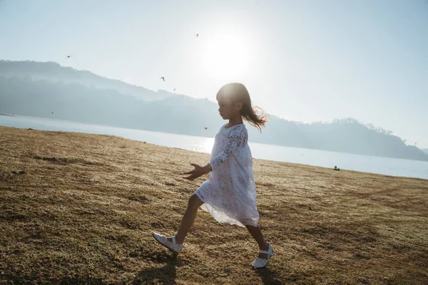 Little girl running on field with enjoy sunrise — ストック写真