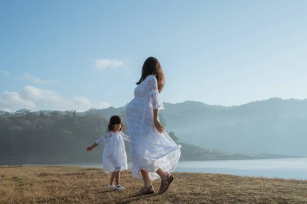 Asiática mãe grávida com filha se divertindo ao nascer do sol — Fotografia de Stock