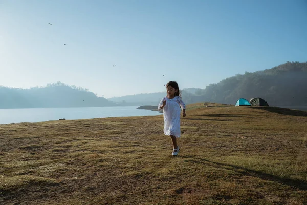 Mała dziewczynka działa na polu z cieszyć się wschodem słońca — Zdjęcie stockowe