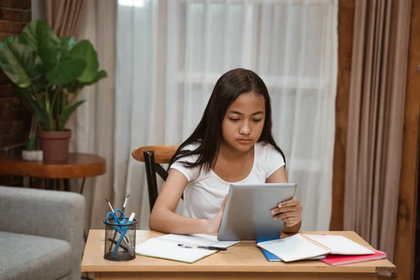 アジアのティーンエイジャーはタブレットを使って家で宿題をしています — ストック写真