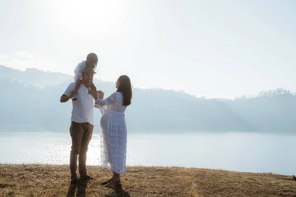 Baba, anne ve kız ayakta gündoğumunun tadını çıkarın. — Stok fotoğraf