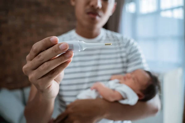 Отец с младенцем и термометром — стоковое фото