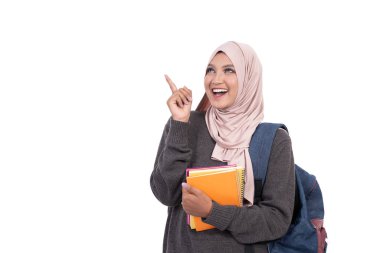 Peçeli öğrenci elleri ile kitapları gösteriyor ve taşıyor.