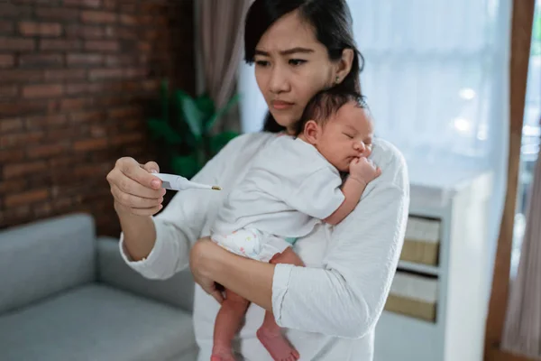 Asian mother measuring temperature to her little baby — Stock Photo, Image