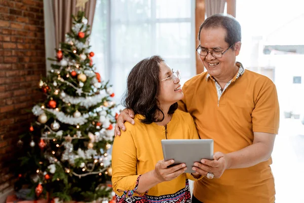 Зрелая пара с помощью планшетного ПК на Рождество — стоковое фото