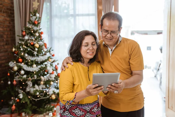 Зрелая пара с помощью планшетного ПК на Рождество — стоковое фото