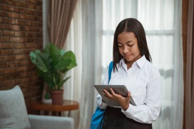 Tablet tutan üniformalı ortaokul öğrencisi.