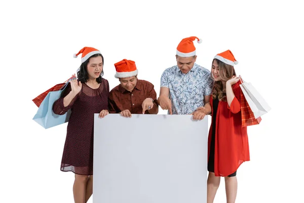 Família com chapéu de santa claus sorrindo segurando placa em branco — Fotografia de Stock