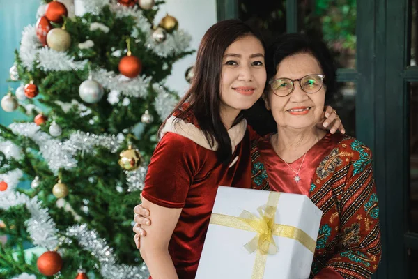 daughter giving surprise gift to senior mother