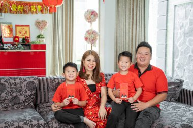 İki oğlu olan Asyalı bir aile ang pao 'yu kucaklıyor kameraya bakıp gülümsüyor